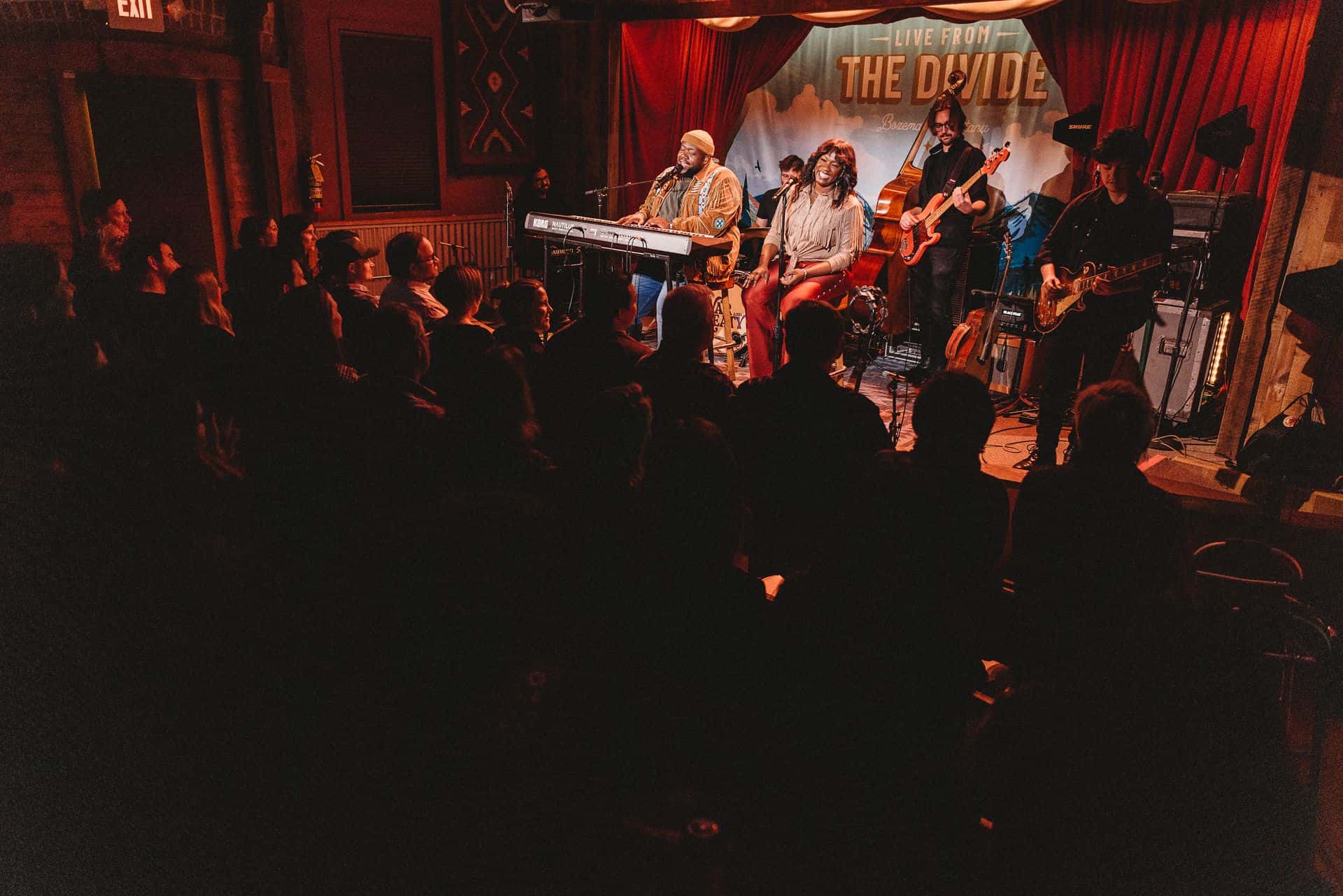 The War and Treaty performing on stage at venue with red lighting and audience.