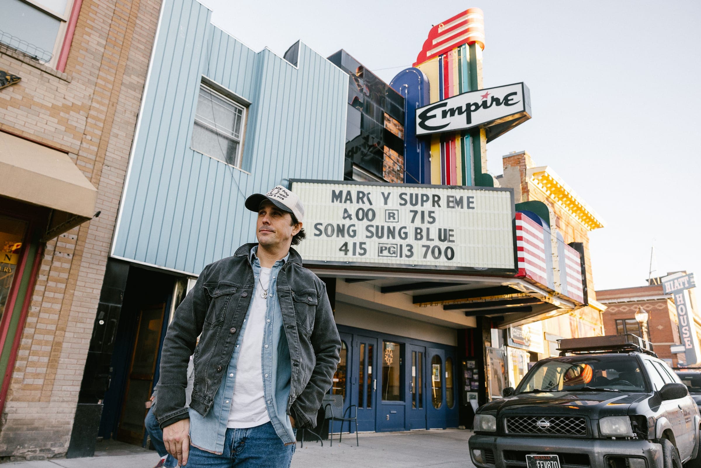 Jason Wickens stands outside Empire theater marquee in classic jacket.